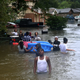People walk down a street flooded by Harvey as they evacuate their homes in Houston.